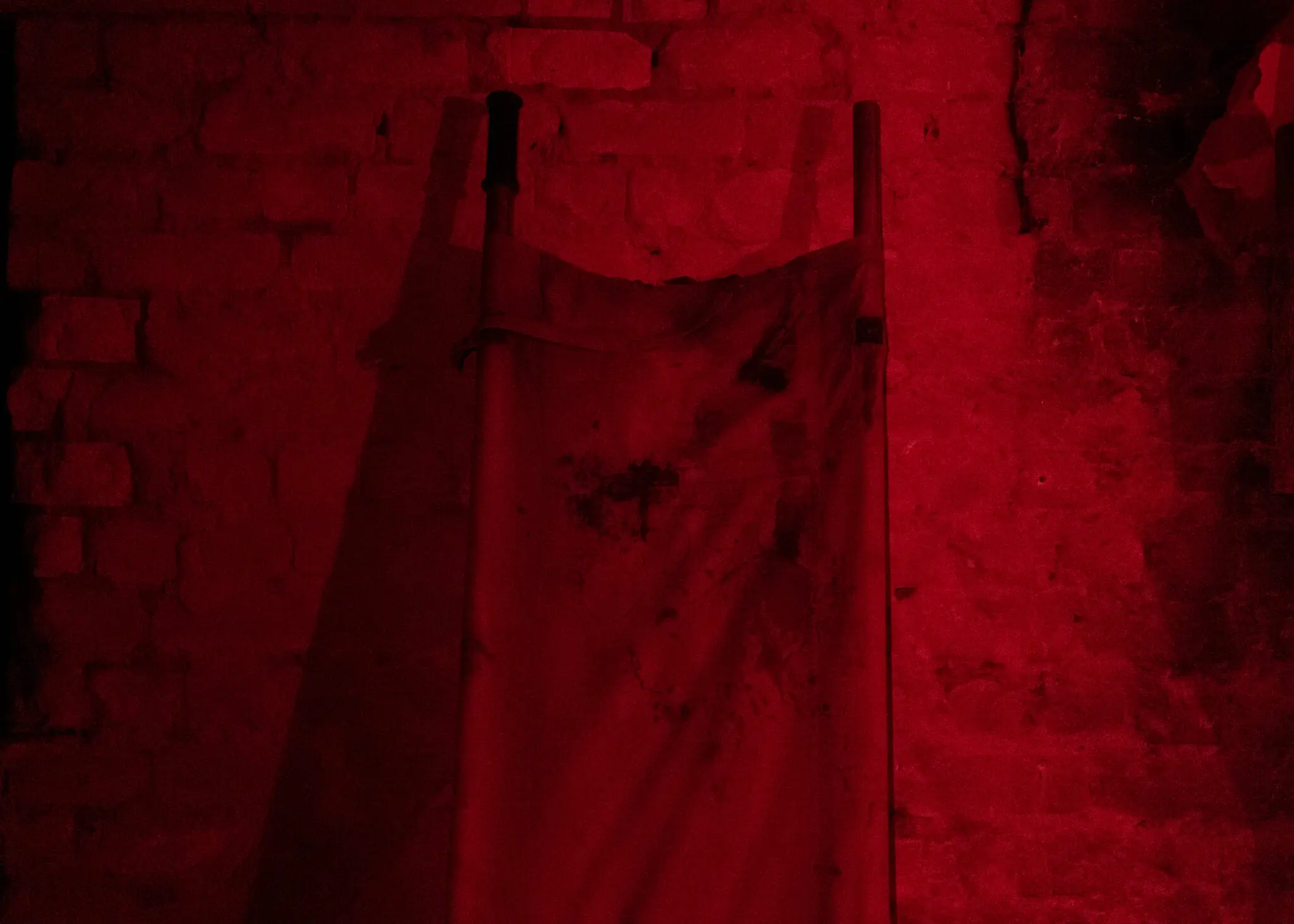 Закривавлені носилки в кутку по центру під світлом червоних вогнів, які використовуються вночі